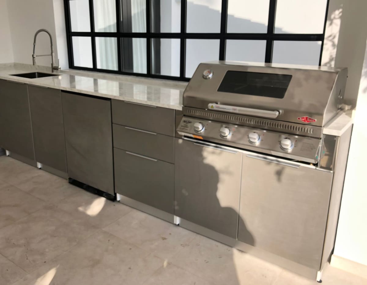Straight-run outdoor kitchen with dark doors, BBQ and sink