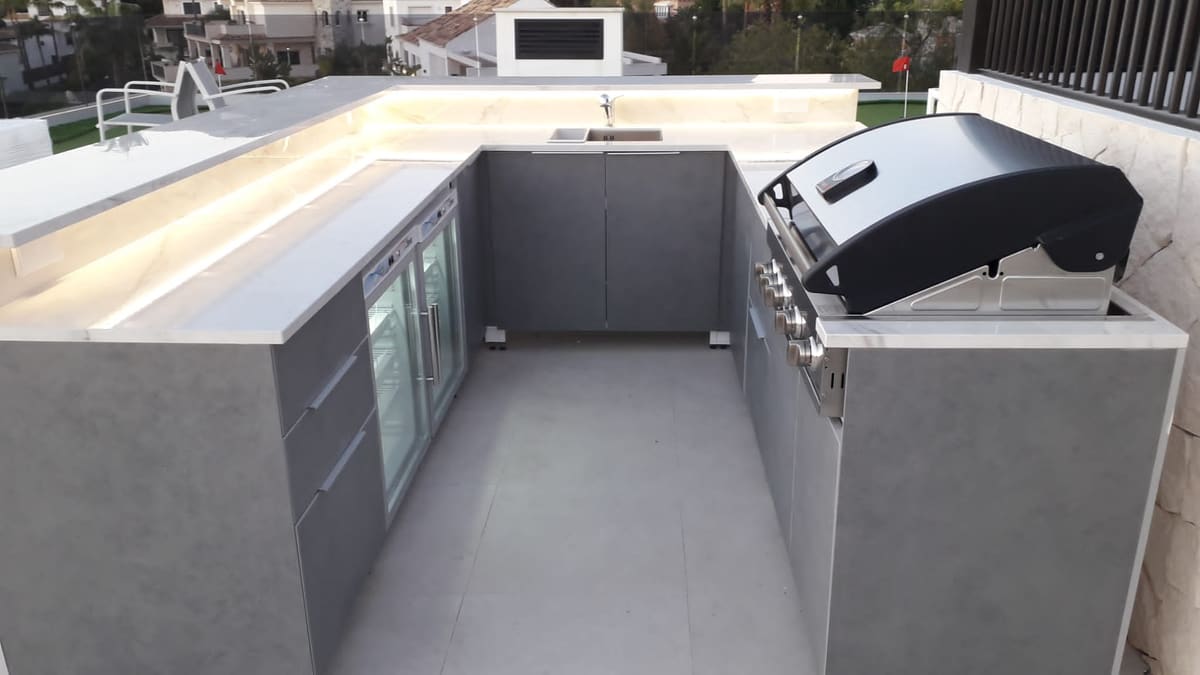 U-shaped outdoor kitchen with LED-lit worktop, glass-door drinks fridges and a built-in BBQ